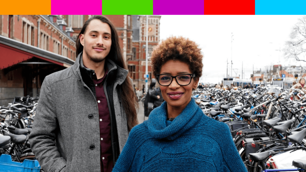 De campagne-foto van Sylvana en Jazie voor de gemeenteraadsverkiezingen in 2018. Sylvana is zwart met een vrij kort kroeskapsel met blonde highlights. Ze draagt een zwarte bril en een blauwe wollen poncho. Jazie is een lichtgekleurde man met lang bruin haar en wat gezichtshaar. Hij draagt een lange grijze jas die open hangt. Een auberginekleurig overhemd eronder.