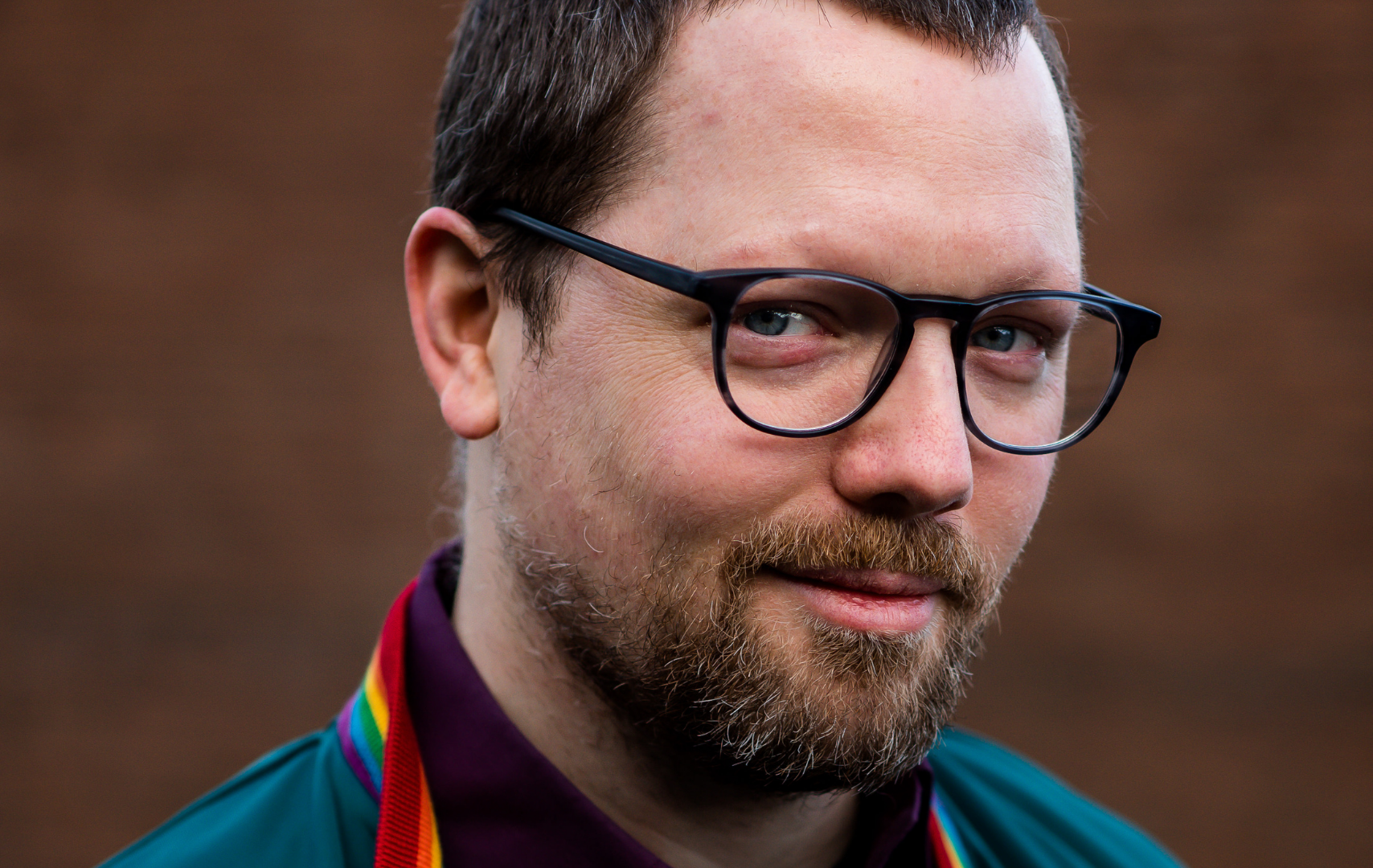 Portretfoto van Bart. Hij heeft een zwarte bril en kort, donker haar. Hij draagt een groen jack met regenboogkraag.