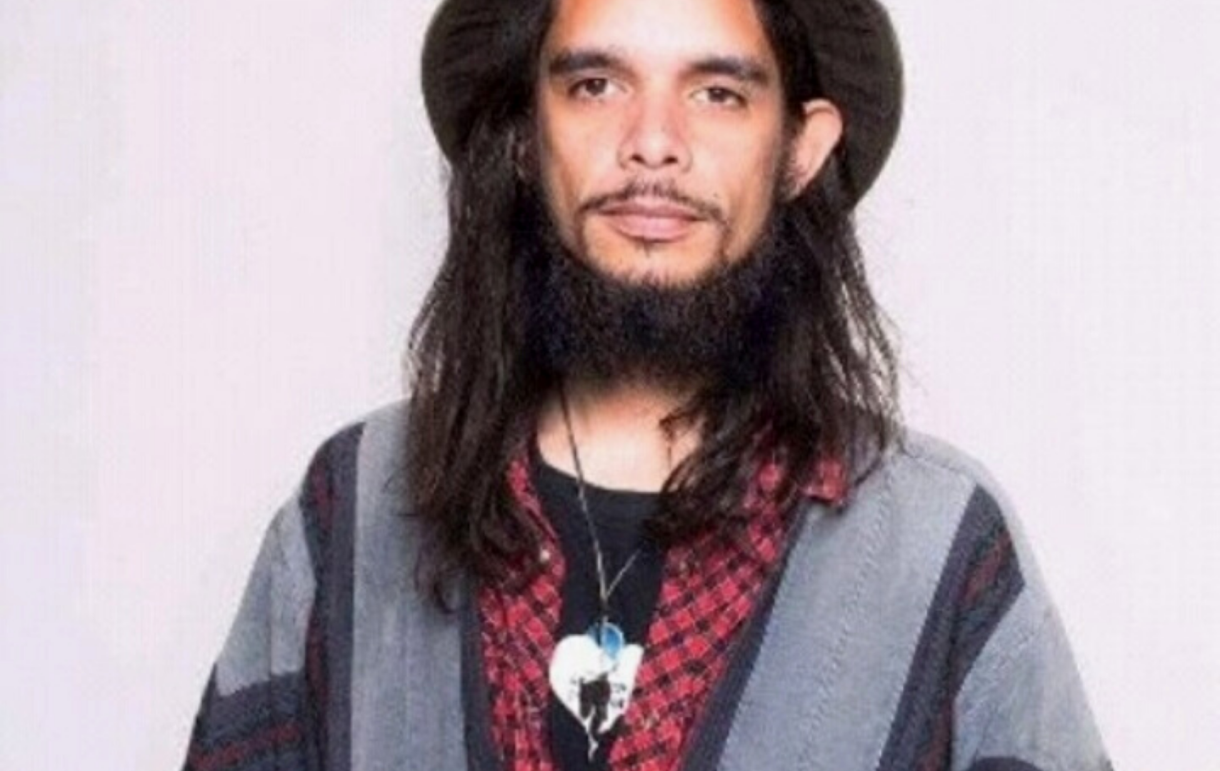 Foto van Miko-Serko. Hij heeft lang donker haar en een baard. Hij draagt een hoed en een rood-zwart shirt. Daaroverheen een grijs jack.