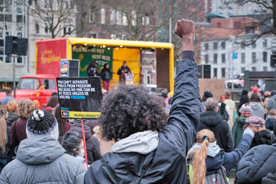 Zwarte activist houdt zijn gebalde vuist omhoog terwijl deze luistert naar een toestraak tijdens een demonstratie