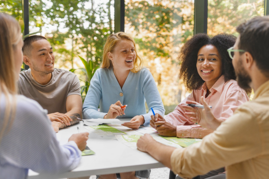 Diverse groep mensen zit aan tafel en bespreekt voorstel