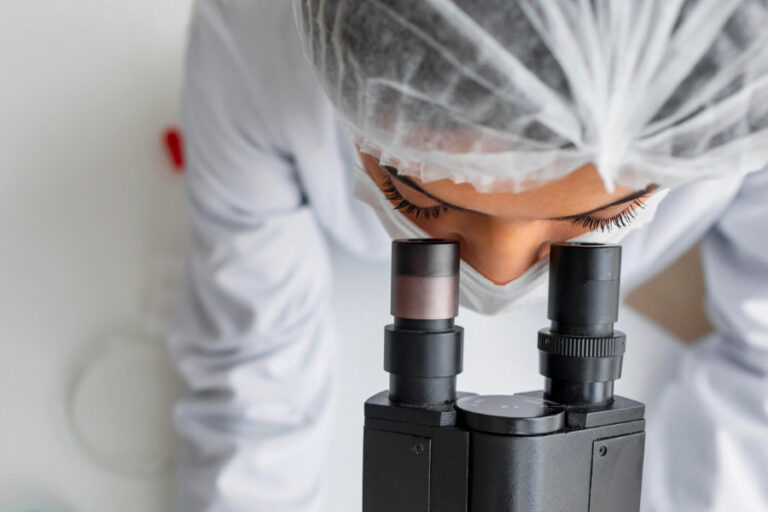 Laborant kijkt in microscoop