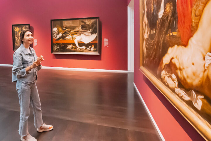 Jonge vrouw in museumzaal met schilderijen