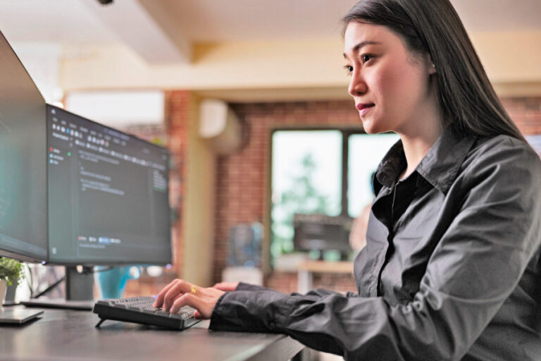 Jonge Aziatische vrouw werkt aan computer in kantoor